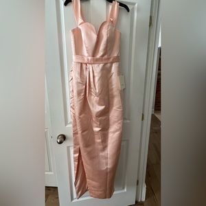A peach coloured long, ballgown dress, with a slit up the side.